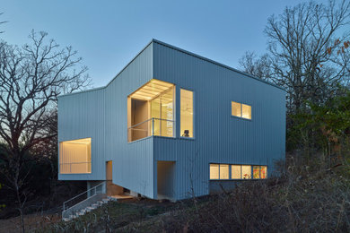 Imagen de fachada de casa blanca y blanca moderna de tamaño medio de tres plantas con revestimiento de metal, techo de mariposa y tejado de metal