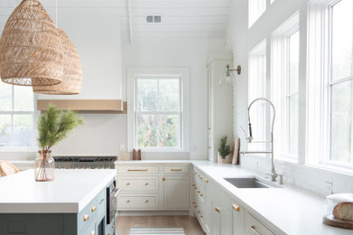 Example of a large beach style l-shaped brown floor kitchen design in Charleston with an undermount sink, beaded inset cabinets, white cabinets, stainless steel appliances, an island and white countertops