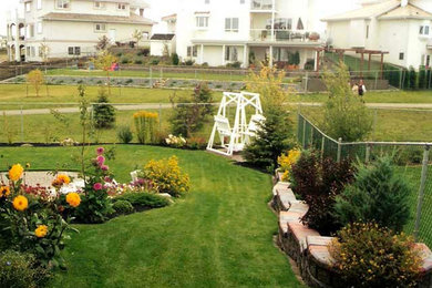 Inspiration for a mid-sized full sun backyard stone retaining wall landscape in Calgary.