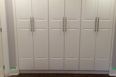 Ejemplo de armario unisex tradicional renovado de tamaño medio con suelo de madera oscura, armarios con paneles con relieve y puertas de armario blancas