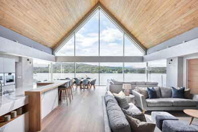 Idée de décoration pour un très grand salon minimaliste avec un mur gris, parquet clair, un téléviseur encastré, un plafond en lambris de bois et du lambris.