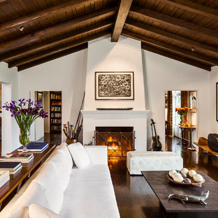Diseño de salón cerrado, mediterráneo, grande, con paredes blancas, suelo de madera oscura, chimenea tradicional y marco de chimenea de yeso
