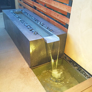 This is an example of a small modern backyard patio in Denver with a water feature and concrete slab.