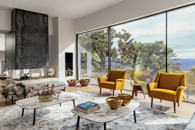Imagen de salón actual con paredes blancas, suelo de madera clara, chimenea de doble cara y suelo beige