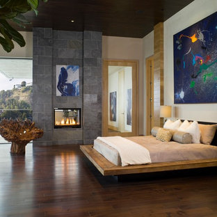 Modernes Schlafzimmer mit beiger Wandfarbe, dunklem Holzboden und Tunnelkamin in Los Angeles
