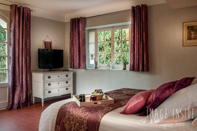 Modelo de dormitorio principal clásico renovado de tamaño medio con paredes rosas, suelo de baldosas de cerámica y suelo rojo