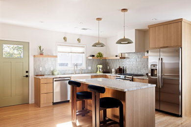 Eat-in kitchen - mid-sized 1960s l-shaped medium tone wood floor eat-in kitchen idea in Los Angeles with a farmhouse sink, flat-panel cabinets, medium tone wood cabinets, granite countertops, blue backsplash, subway tile backsplash, stainless steel appliances, an island and multicolored countertops