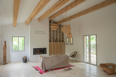Aménagement d'une grande salle de séjour moderne ouverte avec une bibliothèque ou un coin lecture, un mur blanc, un sol en travertin, une cheminée standard, un manteau de cheminée en plâtre, un téléviseur dissimulé, un sol beige, poutres apparentes et éclairage.