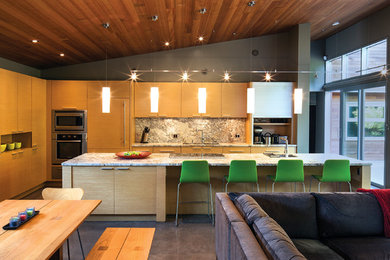 Example of a minimalist galley open concept kitchen design in Vancouver with flat-panel cabinets, light wood cabinets and stainless steel appliances