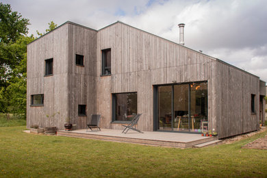Idée de décoration pour une petite façade de maison grise design en bois et planches et couvre-joints à un étage.