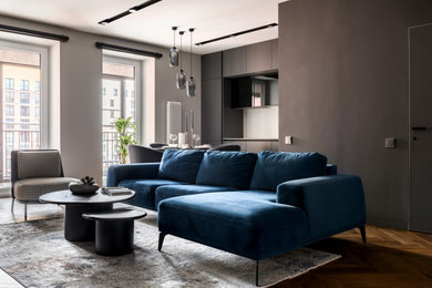 Пример оригинального дизайна: серо-белая гостиная комната среднего размера в современном стиле с музыкальной комнатой, синими стенами, паркетным полом среднего тона, телевизором на стене, зоной отдыха, панелями на части стены и синим диваном