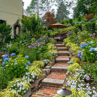 Photo of a huge traditional partial sun hillside brick landscaping in New York.