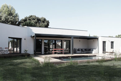 Réalisation d'une façade de maison blanche méditerranéenne de taille moyenne et à un étage avec un toit à deux pans et un toit en tuile.