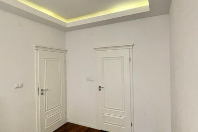 Example of a mid-sized transitional dark wood floor, brown floor and tray ceiling hallway design in New York with white walls