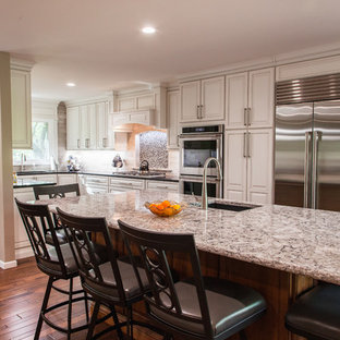 Zweizeilige, Große Klassische Küche mit Vorratsschrank, Unterbauwaschbecken, profilierten Schrankfronten, weißen Schränken, Quarzit-Arbeitsplatte, bunter Rückwand, Kalk-Rückwand, Küchengeräten aus Edelstahl, braunem Holzboden, Kücheninsel und braunem Boden in Wichita