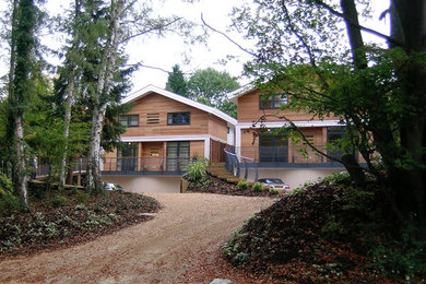Foto de fachada de casa marrón actual grande de tres plantas con revestimientos combinados, tejado a dos aguas y tejado de teja de barro