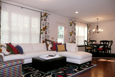 Modelo de sala de estar abierta contemporánea grande con paredes blancas, suelo de madera en tonos medios, estufa de leña, marco de chimenea de ladrillo y suelo marrón