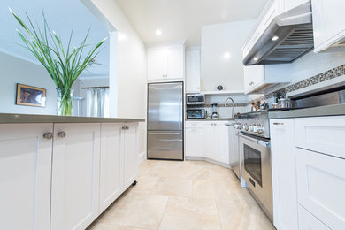 Inspiration for a large traditional u-shaped separate kitchen in San Francisco with white splashback, subway tile splashback, stainless steel appliances, marble floors, beige floor, shaker cabinets, white cabinets, solid surface benchtops and with island.