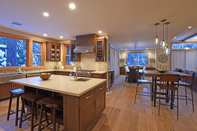 Large trendy u-shaped light wood floor and beige floor open concept kitchen photo in Other with an undermount sink, shaker cabinets, dark wood cabinets, beige backsplash, mosaic tile backsplash, stainless steel appliances and an island