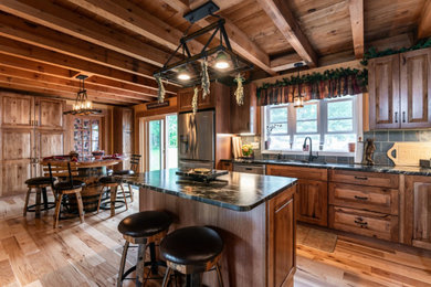 Idéer för att renovera ett rustikt svart svart l-kök, med en undermonterad diskho, luckor med upphöjd panel, skåp i mellenmörkt trä, granitbänkskiva, grått stänkskydd, rostfria vitvaror, mellanmörkt trägolv och en köksö