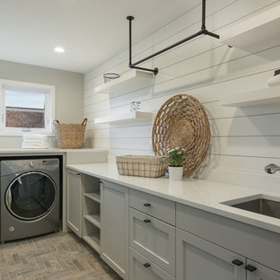 Inspiration for a medium sized contemporary l-shaped separated utility room in Seattle with a submerged sink, shaker cabinets, grey cabinets, composite countertops, white walls, brick flooring, a side by side washer and dryer and red floors.