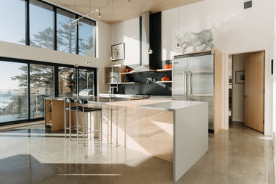 Example of a large minimalist single-wall concrete floor and gray floor eat-in kitchen design in Vancouver with an undermount sink, flat-panel cabinets, white cabinets, quartz countertops, black backsplash, stone tile backsplash, stainless steel appliances, an island and gray countertops