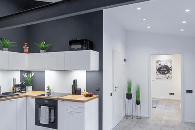 Kleine Industrial Wohnküche ohne Kamin mit grauer Wandfarbe, grauem Boden und freigelegten Dachbalken in Düsseldorf