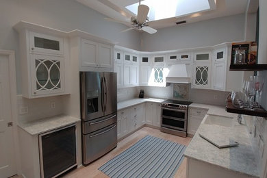 Large trendy u-shaped light wood floor eat-in kitchen photo in Tampa with a farmhouse sink, shaker cabinets, white cabinets, marble countertops and no island