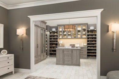 Expansive modern gender-neutral walk-in wardrobe in Chicago with shaker cabinets, beige floor and grey cabinets.