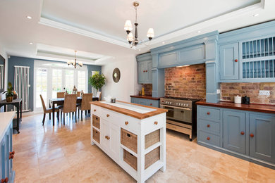 Design ideas for a traditional eat-in kitchen in London with recessed-panel cabinets, blue cabinets and wood benchtops.