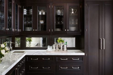 Elegant l-shaped ceramic tile kitchen pantry photo in New York with shaker cabinets, dark wood cabinets, marble countertops, brown backsplash, mirror backsplash, paneled appliances and an island