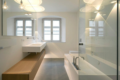 Modernes Badezimmer mit flächenbündigen Schrankfronten, Mineralwerkstoff-Waschtisch, weißer Waschtischplatte, Doppelwaschbecken, schwebendem Waschtisch, hellbraunen Holzschränken und integriertem Waschbecken in München