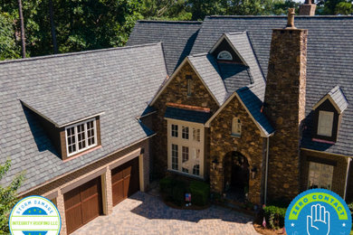 Inspiration for a large timeless beige three-story brick house exterior remodel in Charlotte with a hip roof and a shingle roof
