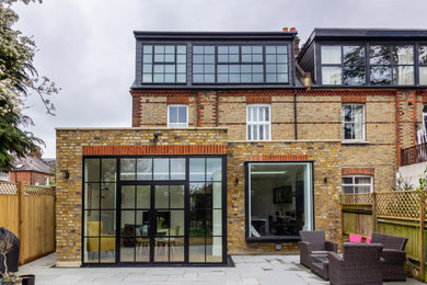 Photo of a medium sized contemporary two floor brick and rear house exterior in London with a tiled roof and a grey roof.