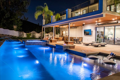 Large beach style backyard custom-shaped lap hot tub photo in Orange County with decking