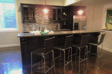 Photo of a traditional kitchen in Birmingham with a submerged sink, recessed-panel cabinets, black cabinets, engineered stone countertops, mosaic tiled splashback, stainless steel appliances, concrete flooring and an island.