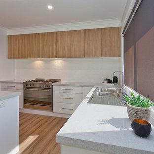 Свежая идея для дизайна: большая угловая кухня в современном стиле с кладовкой, накладной раковиной, плоскими фасадами, светлыми деревянными фасадами, столешницей из кварцевого композита, белым фартуком, фартуком из керамической плитки, техникой из нержавеющей стали, полом из линолеума, островом, коричневым полом и серой столешницей - отличное фото интерьера