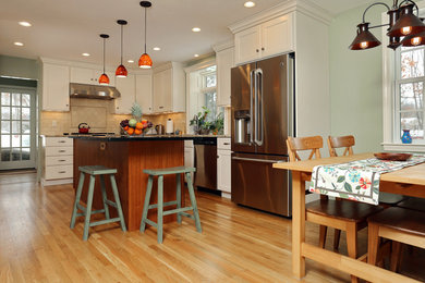Inspiration for a mid-sized country l-shaped light wood floor eat-in kitchen remodel in Providence with stainless steel appliances, an island, shaker cabinets, white cabinets, granite countertops, beige backsplash, ceramic backsplash and a double-bowl sink
