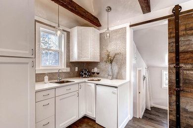 Example of a small transitional l-shaped medium tone wood floor open concept kitchen design in Denver with a drop-in sink, recessed-panel cabinets, white cabinets, solid surface countertops, beige backsplash, mosaic tile backsplash and white appliances