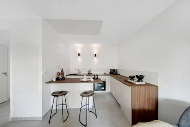 Inspiration pour une cuisine américaine design en L de taille moyenne avec un évier encastré, un plan de travail en bois, une crédence blanche, une crédence en céramique, un électroménager en acier inoxydable, îlot et un plan de travail marron.