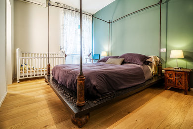 This is an example of a mid-sized traditional master bedroom in Rome with green walls, medium hardwood floors, no fireplace and brown floor.