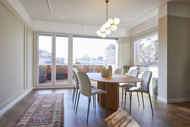 Foto di una grande sala da pranzo aperta verso il soggiorno boho chic con pareti beige, parquet chiaro e boiserie