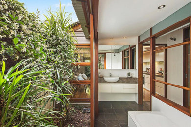 Expansive tropical master bathroom in Sydney with flat-panel cabinets, white cabinets, a corner tub, a two-piece toilet, white tile, beige walls, an integrated sink, an open shower, a single vanity and a floating vanity.