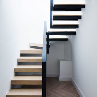 Photo of a large modern wood u-shaped staircase in London with open risers.