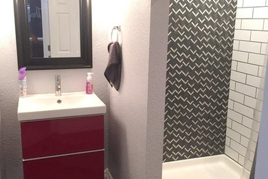 Example of a mid-sized trendy 3/4 black tile, black and white tile, gray tile and porcelain tile porcelain tile and gray floor bathroom design in Denver with flat-panel cabinets, red cabinets, a one-piece toilet, gray walls, an integrated sink and solid surface countertops