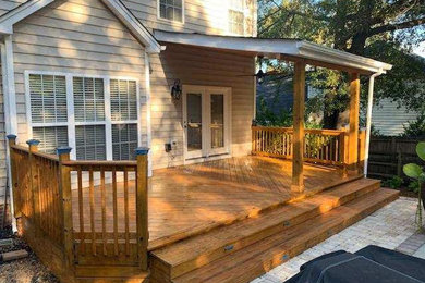 Example of a mid-sized classic backyard deck design in Charlotte with a roof extension