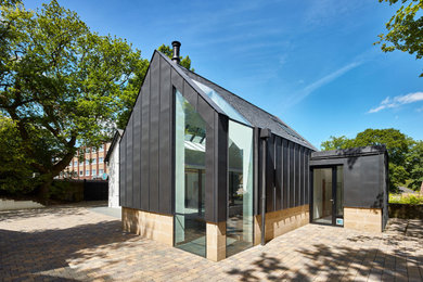 Diseño de fachada de casa gris contemporánea de tamaño medio de dos plantas con revestimiento de metal, tejado a dos aguas y tejado de teja de barro