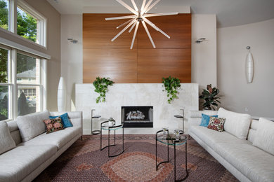 Diseño de salón minimalista grande con paredes beige, suelo de madera oscura, chimenea de doble cara, marco de chimenea de piedra y suelo marrón