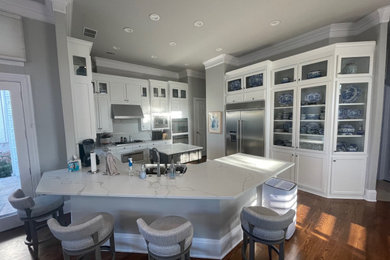 Enclosed kitchen - large modern u-shaped medium tone wood floor and brown floor enclosed kitchen idea in Dallas with an undermount sink, shaker cabinets, white cabinets, quartz countertops, white backsplash, quartz backsplash, stainless steel appliances, an island and white countertops