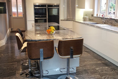 Contemporary kitchen in Hampshire with granite benchtops and limestone floors.
